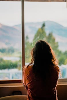 pexels-photo-3029699-3029699 Silhouette of a woman looking out a window at a scenic mountain view in Cajamarca, Peru.